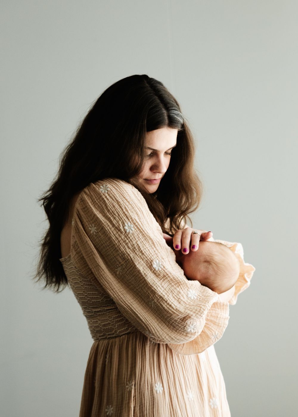 A series of lifestyle photos showing a parent in a cream sweater holding and bonding with a newborn baby.