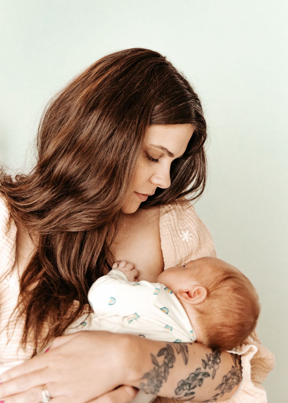A tender moment between parent and baby during a breastfeeding photography session with soft natural lighting.