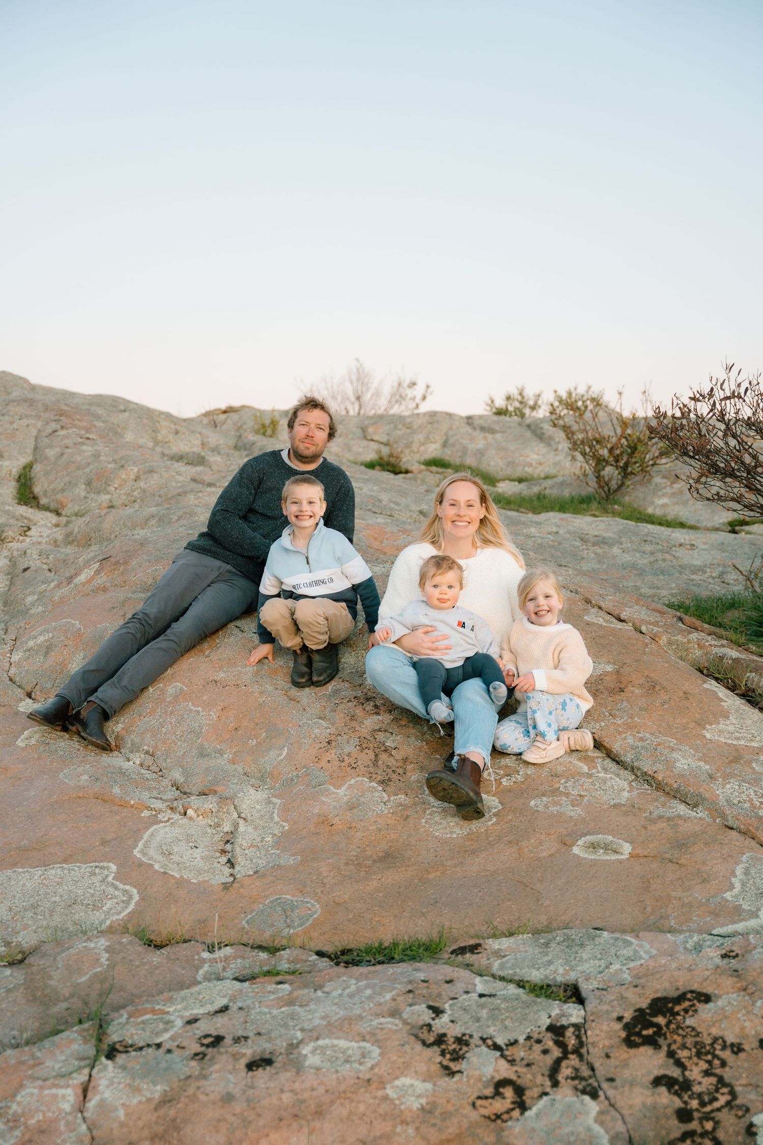 A casual family photo session on rocky terrain during sunset.