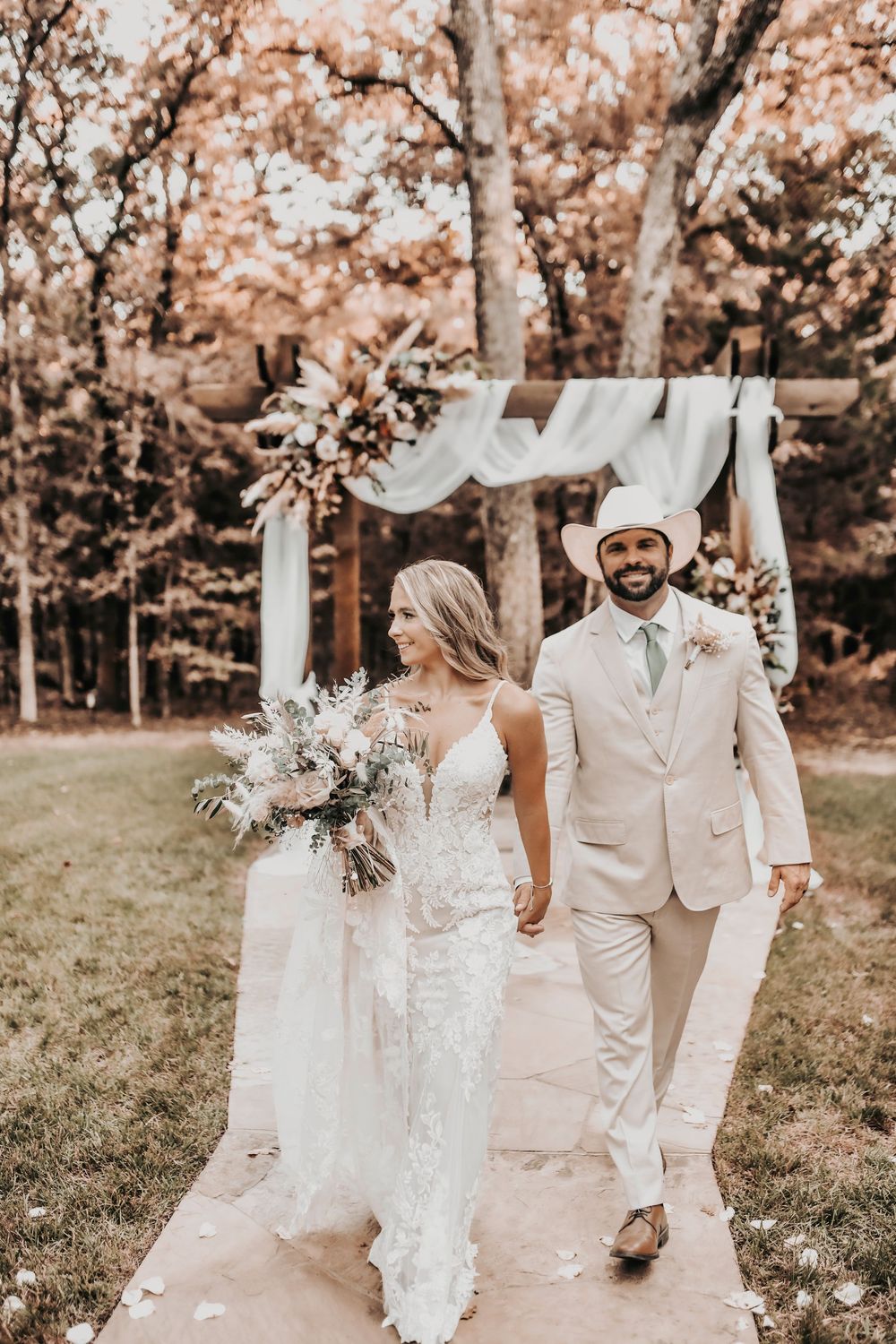 Bride and groom holding hands on the Whispering Oaks altar with rustic greenery and elegant florals