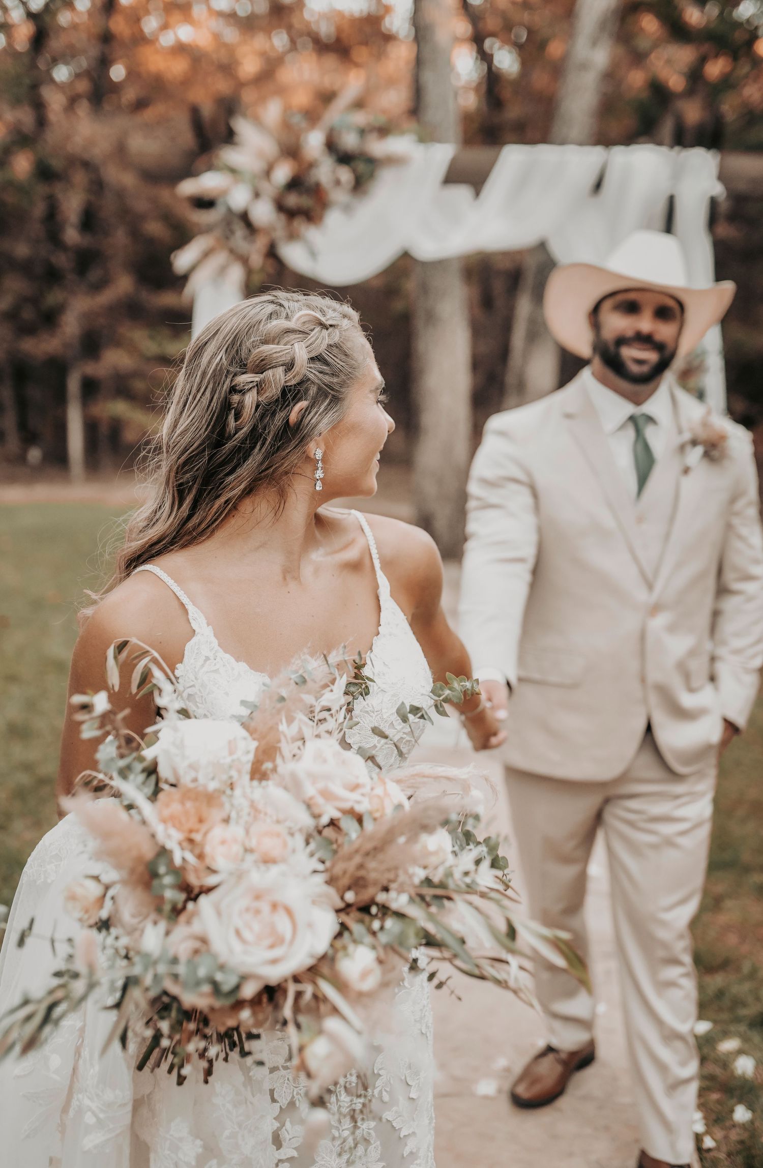 Bride and groom holding hands on the Whispering Oaks altar with rustic greenery and elegant florals