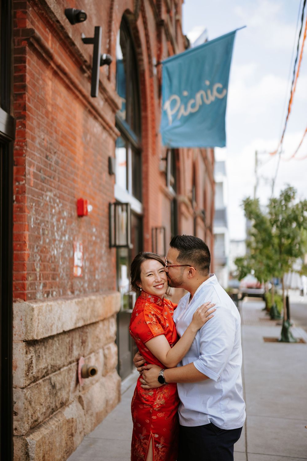 A series of three romantic engagement photos showing a couple in traditional dress against a red brick wall background. Picnic Philadelphia