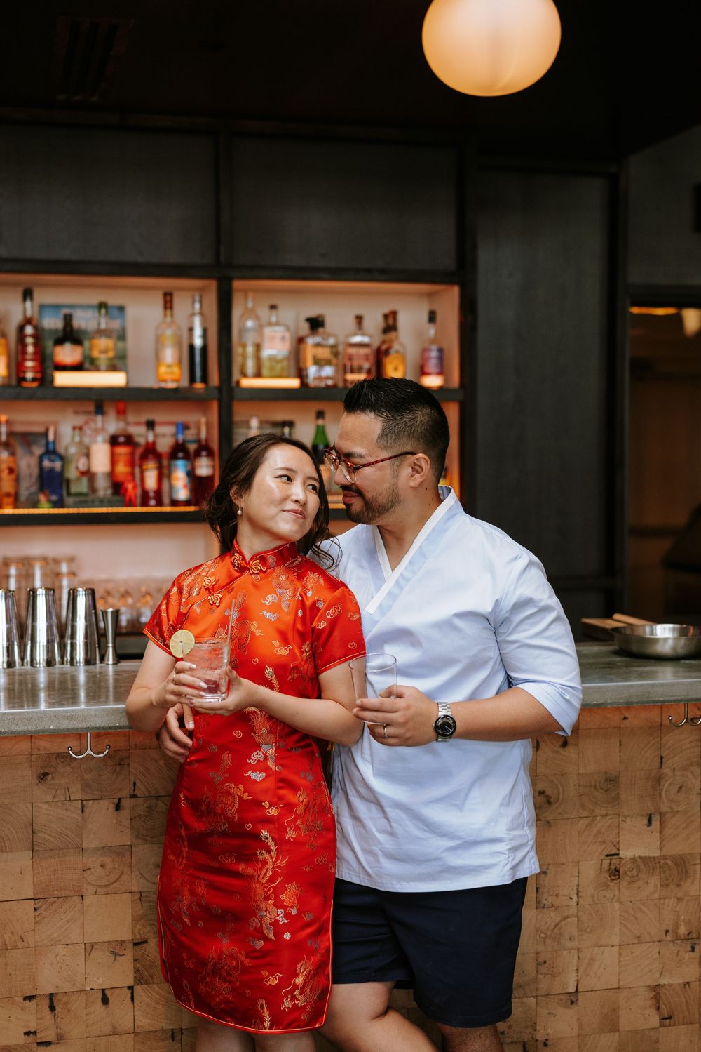 Couple shares romantic moment at bar counter with woman in red traditional qipao dress and man in white shirt. Picnic Philadelphia