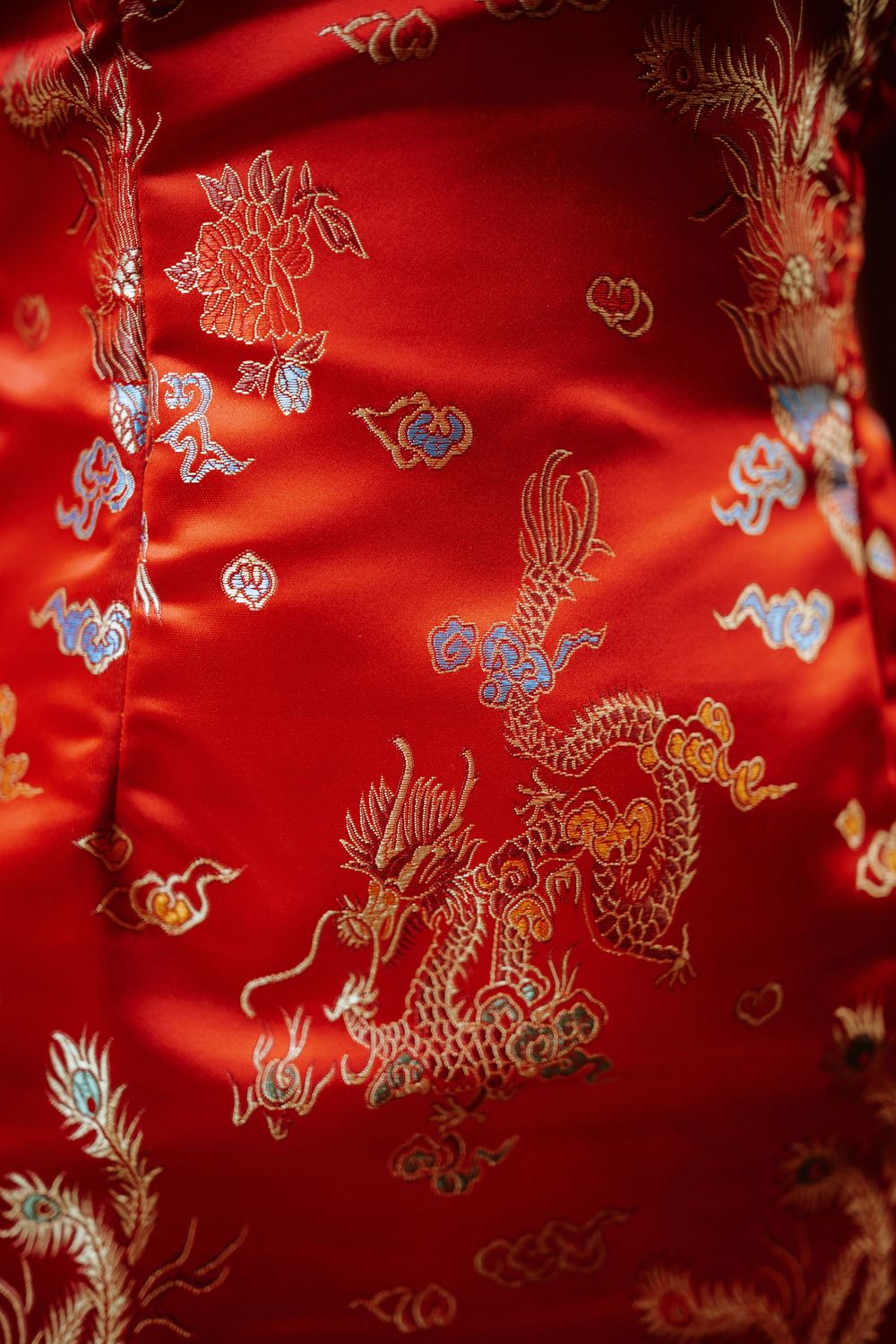 Vibrant red Chinese silk fabric with intricate gold and silver embroidered patterns of butterflies and floral motifs. Picnic Philadelphia
