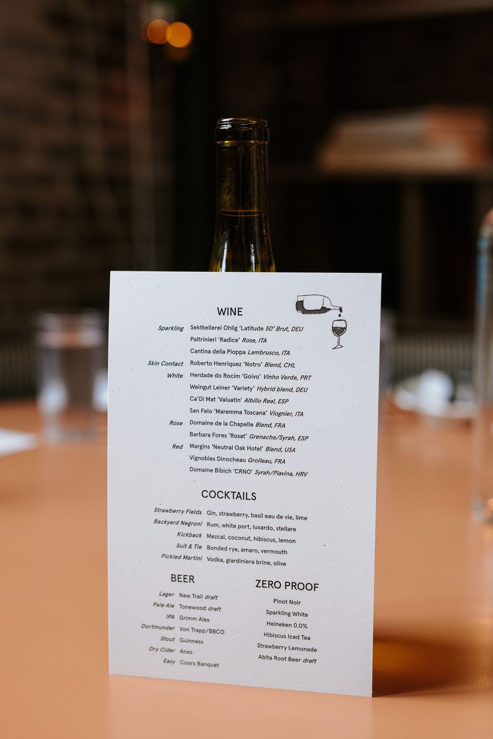 Restaurant menu card showing wine, cocktails, beer, and zero proof drink options on a wooden table. Picnic Philadelphia