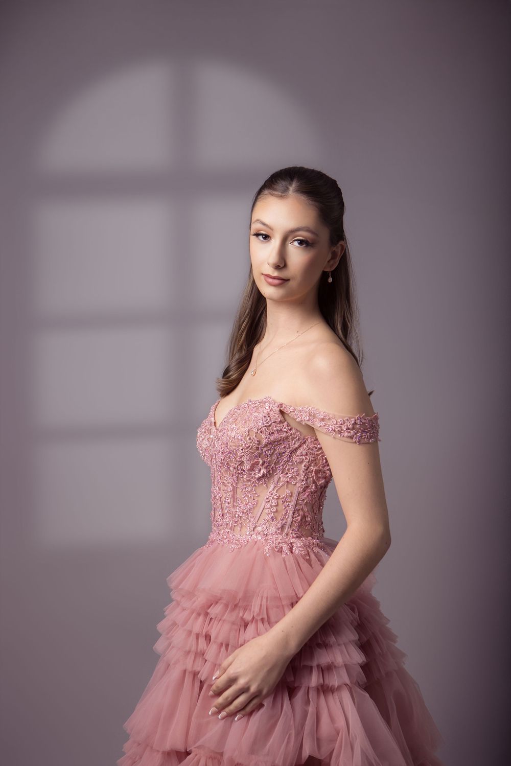 A series of four maternity portraits showing a pink tulle dress with lace details against a gray studio backdrop.