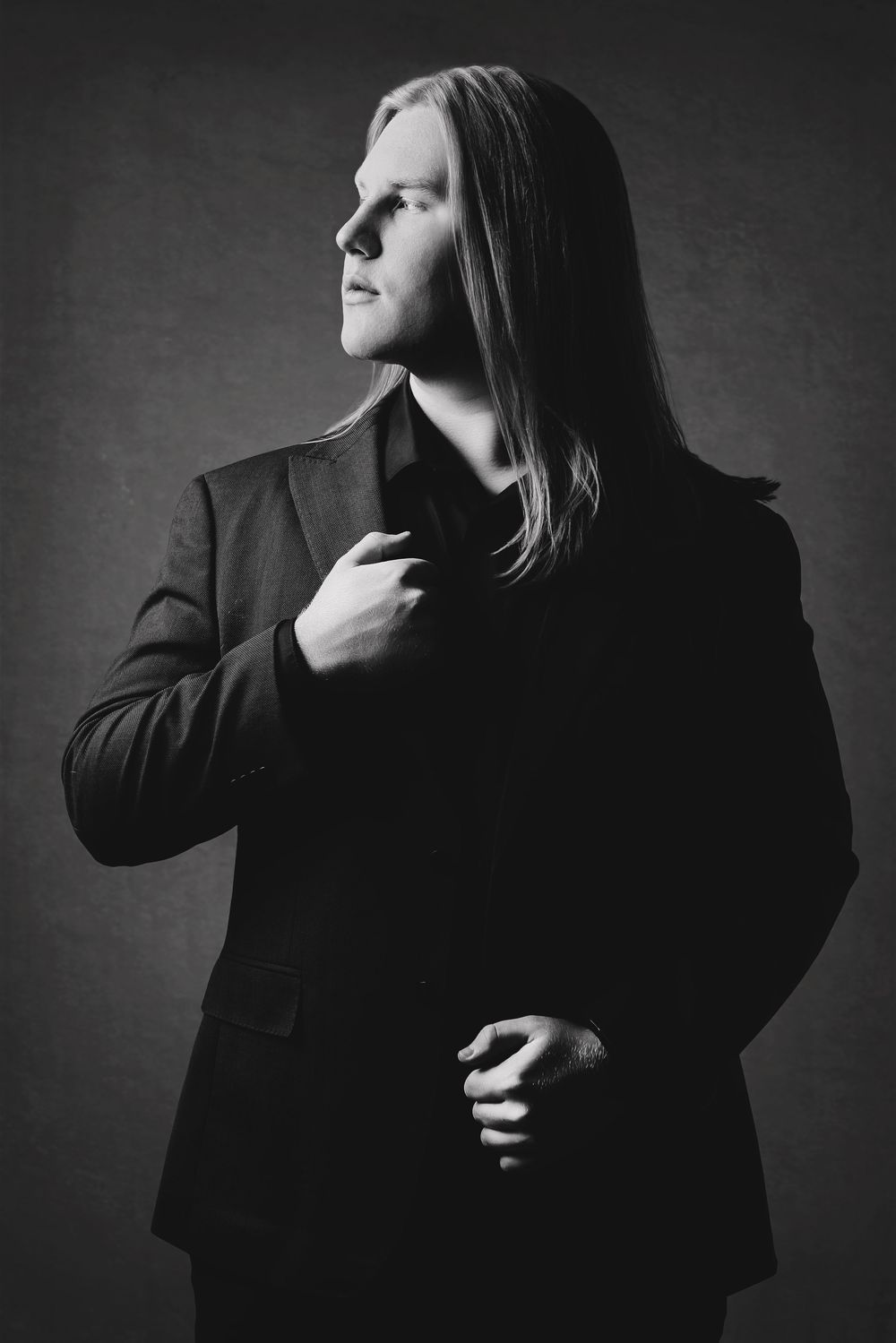 A dramatic black and white portrait series showing a person in dark clothing making expressive poses against a gray background. Grad photo