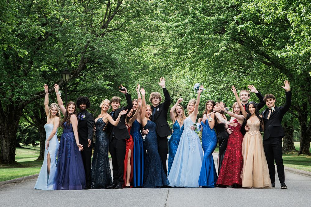 Wedding party poses joyfully together in a vibrant outdoor garden setting with varied formal attire. Grad part portraits