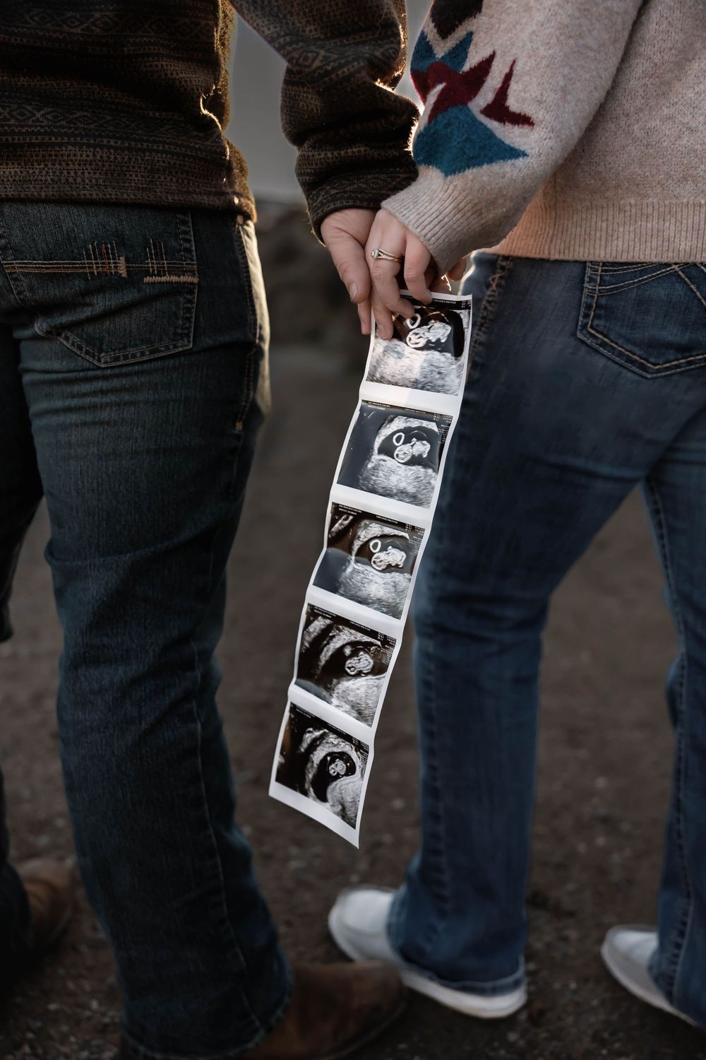 Close-up of hands holding ultrasound photos during pregnancy announcement.