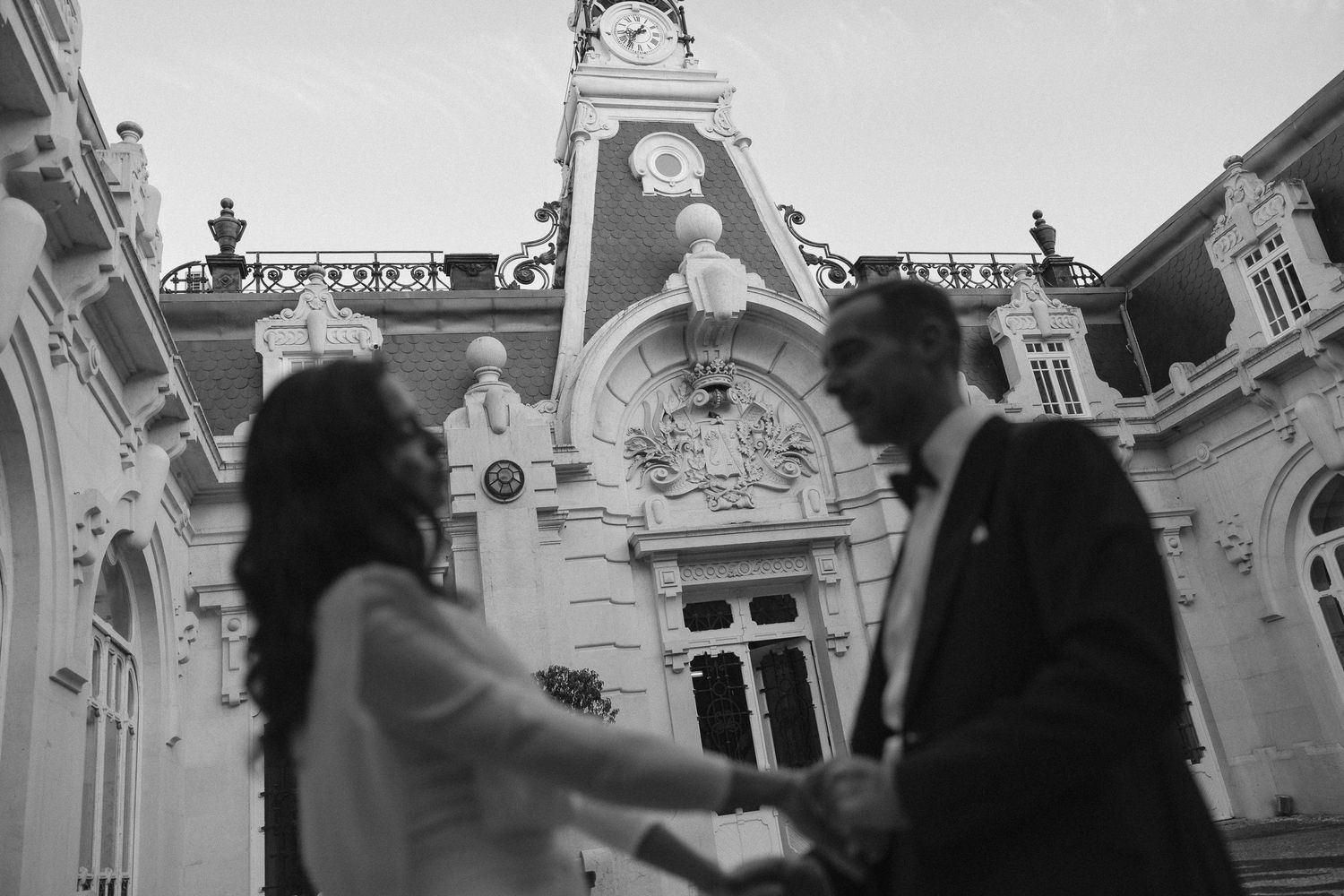 A joyful couple holds hands and walks together during an outdoor wedding celebration as guests look on.