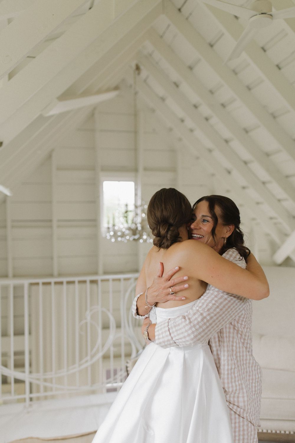 A tender moment captured in a white loft space as two figures embrace warmly.