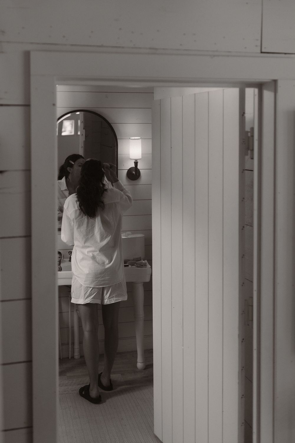 Black and white image of person in robe at bathroom vanity.