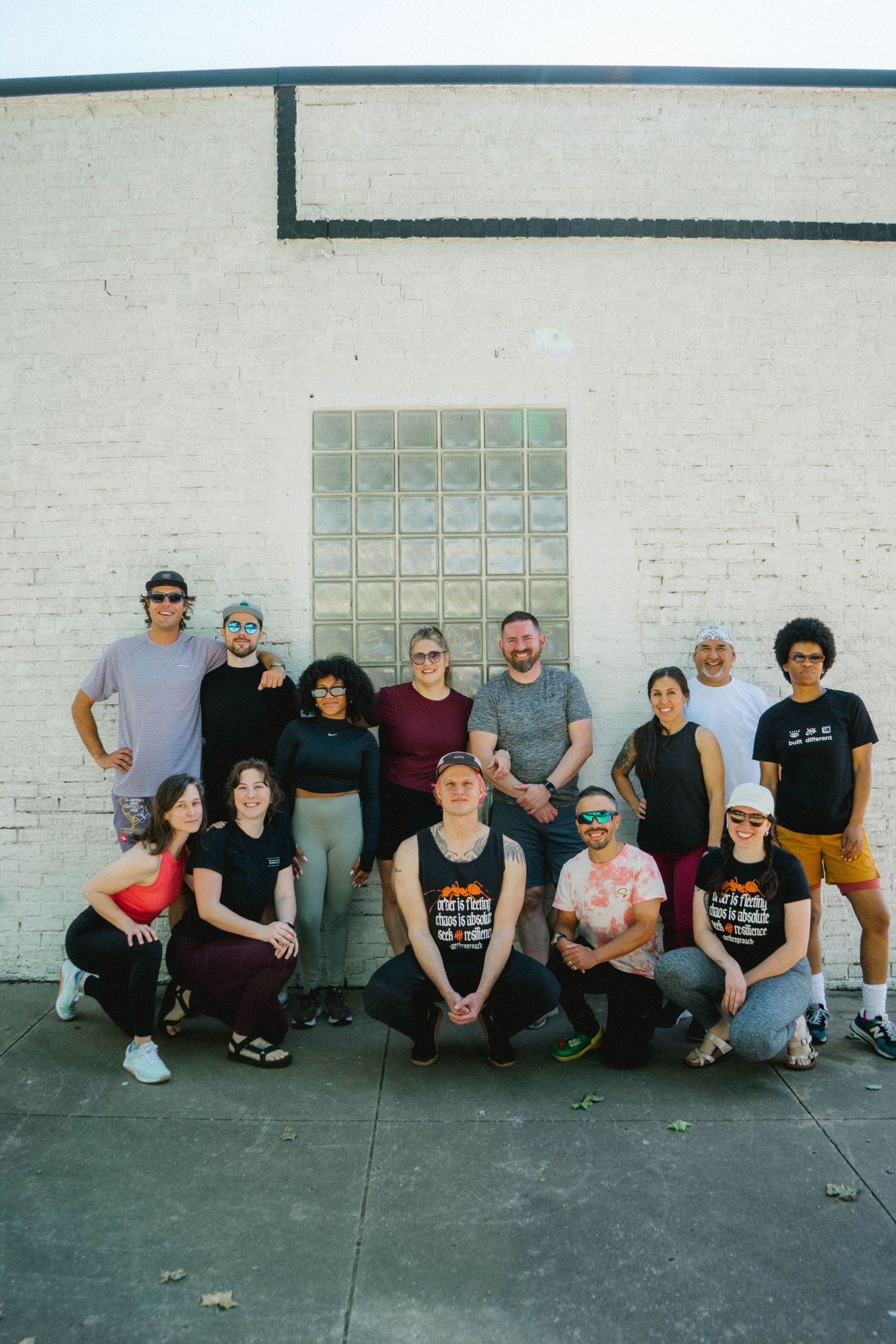 Group photo of team members sitting casually against white brick wall.