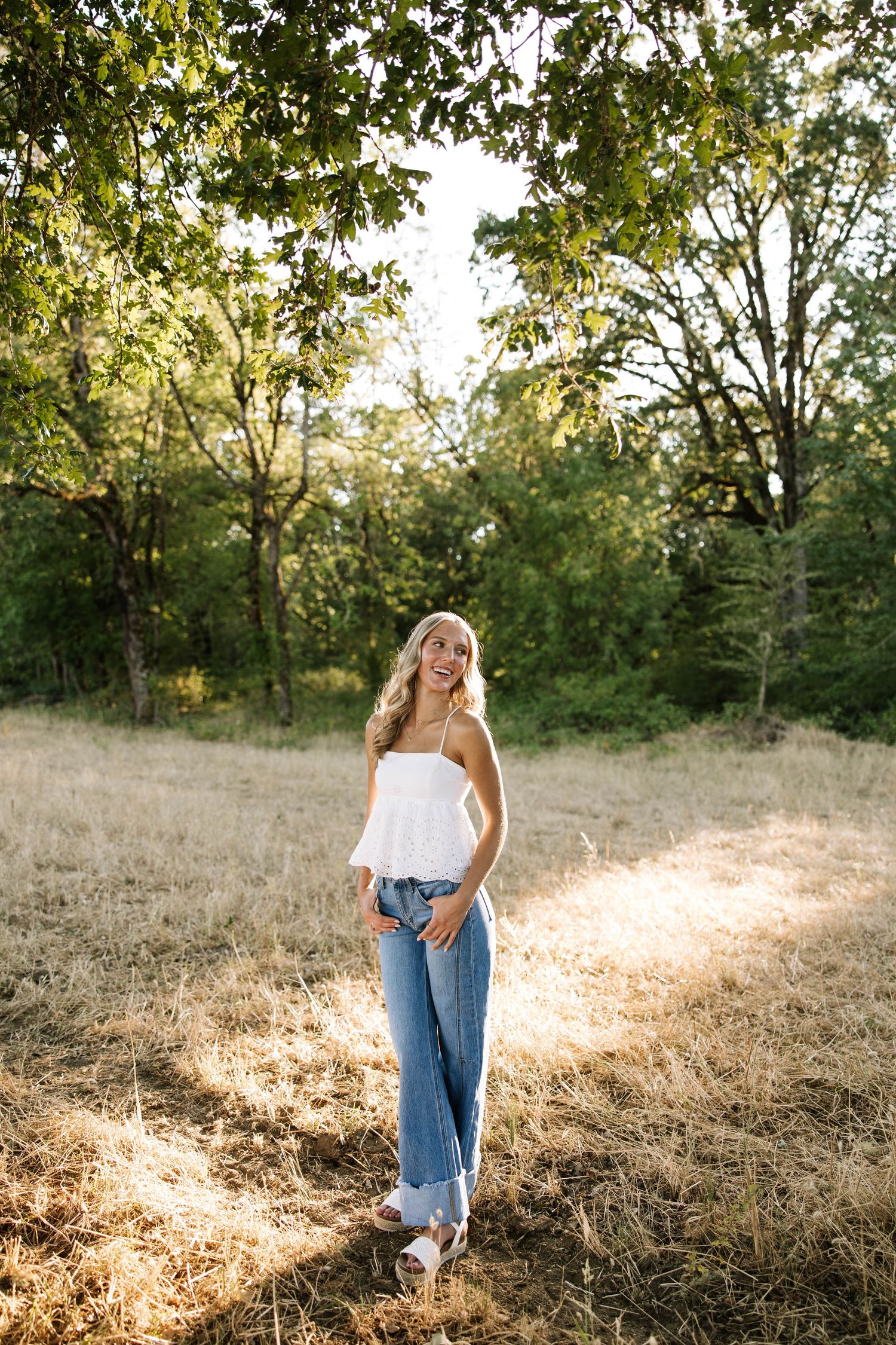 A dreamy golden-hour photoshoot in a sun-drenched field with tall grass and trees.