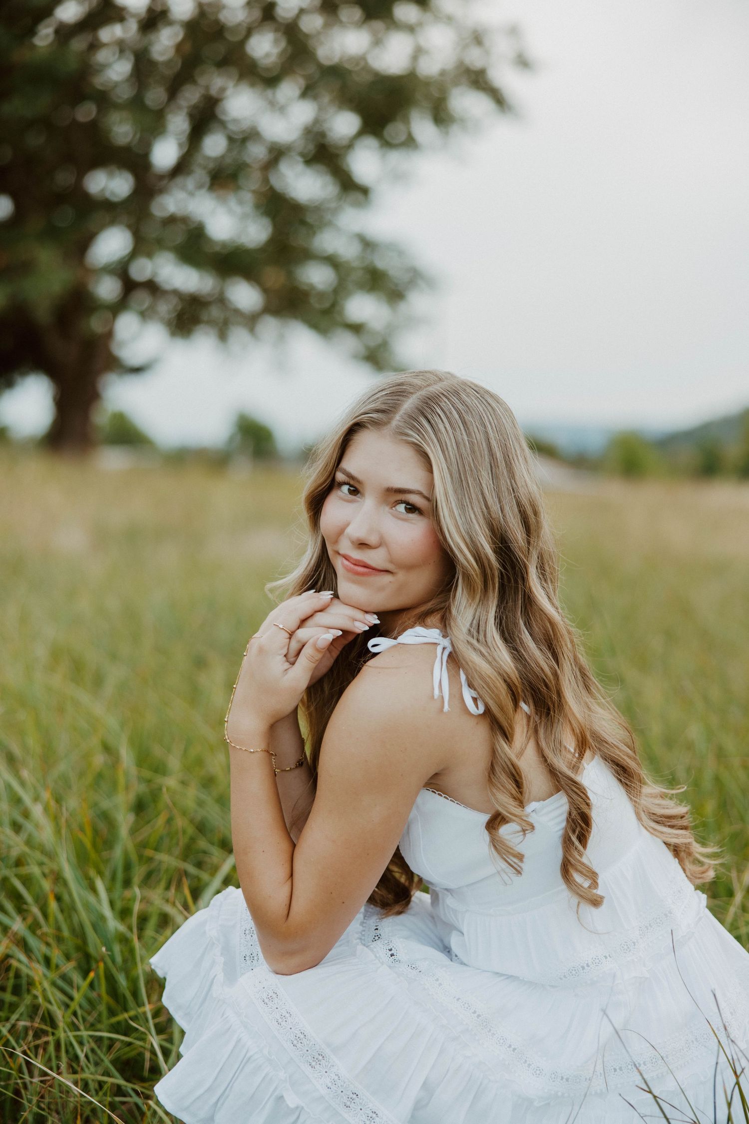 Romantic portrait in white dress among tall grass field.