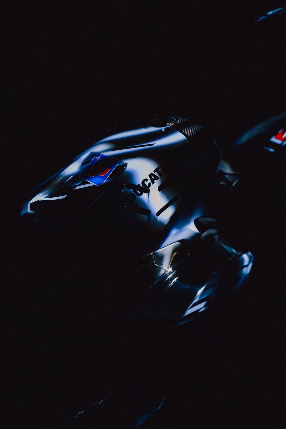 Dark silhouette of a motorcycle against black background with dramatic blue lighting highlights.
