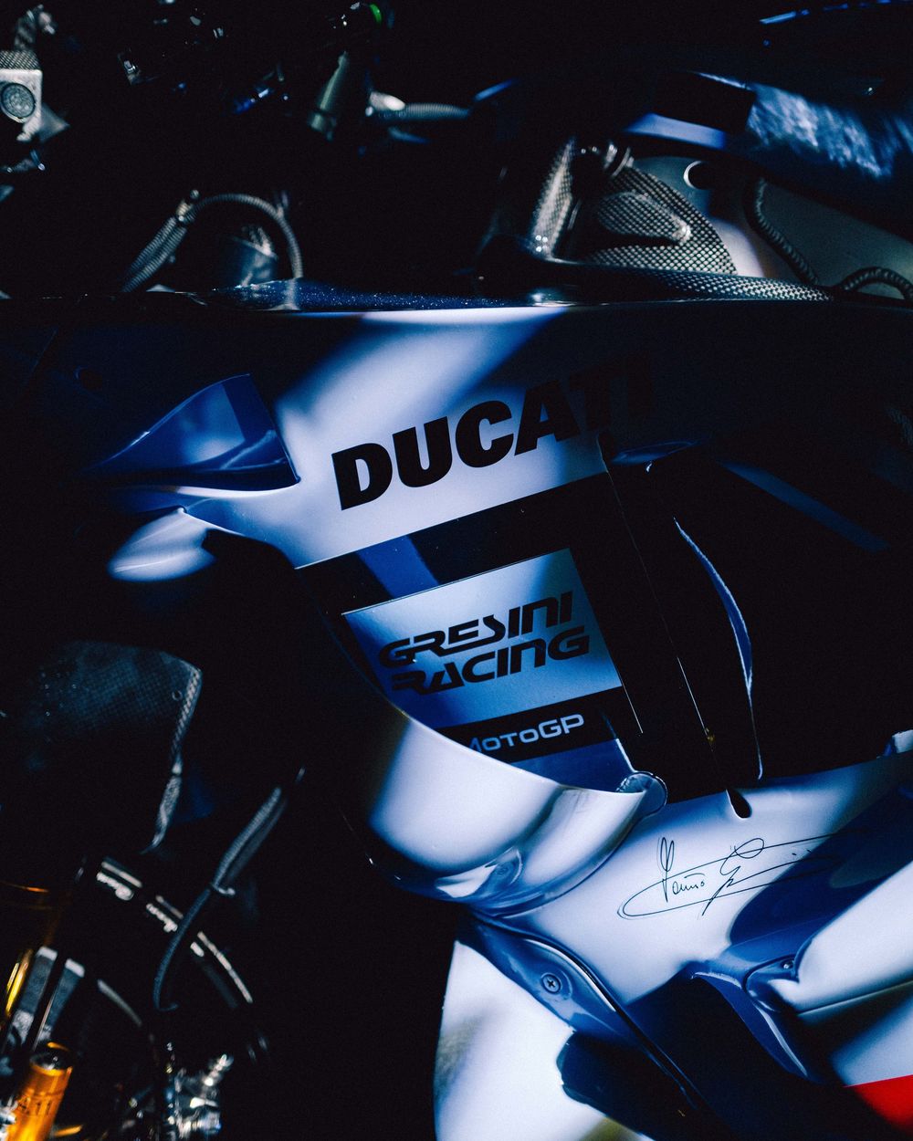 Dramatic close-up shots of silver Ducati motorcycles in low-key lighting with blue highlights and shadows.