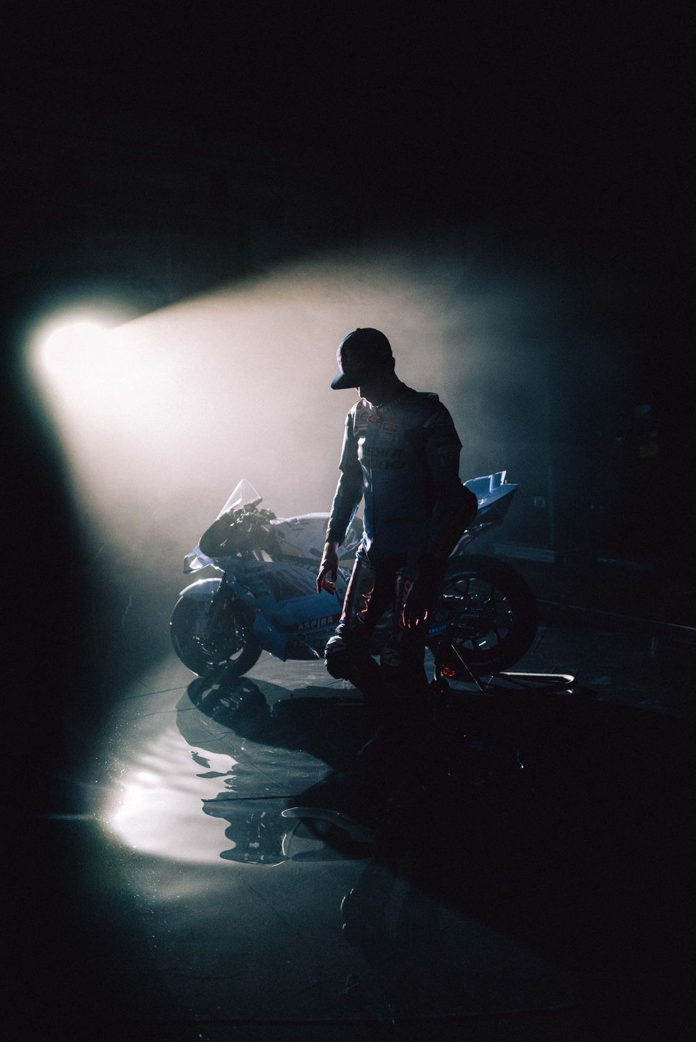 A silhouetted figure rides a motorcycle through dramatic backlit fog in a moody, cinematic sequence.