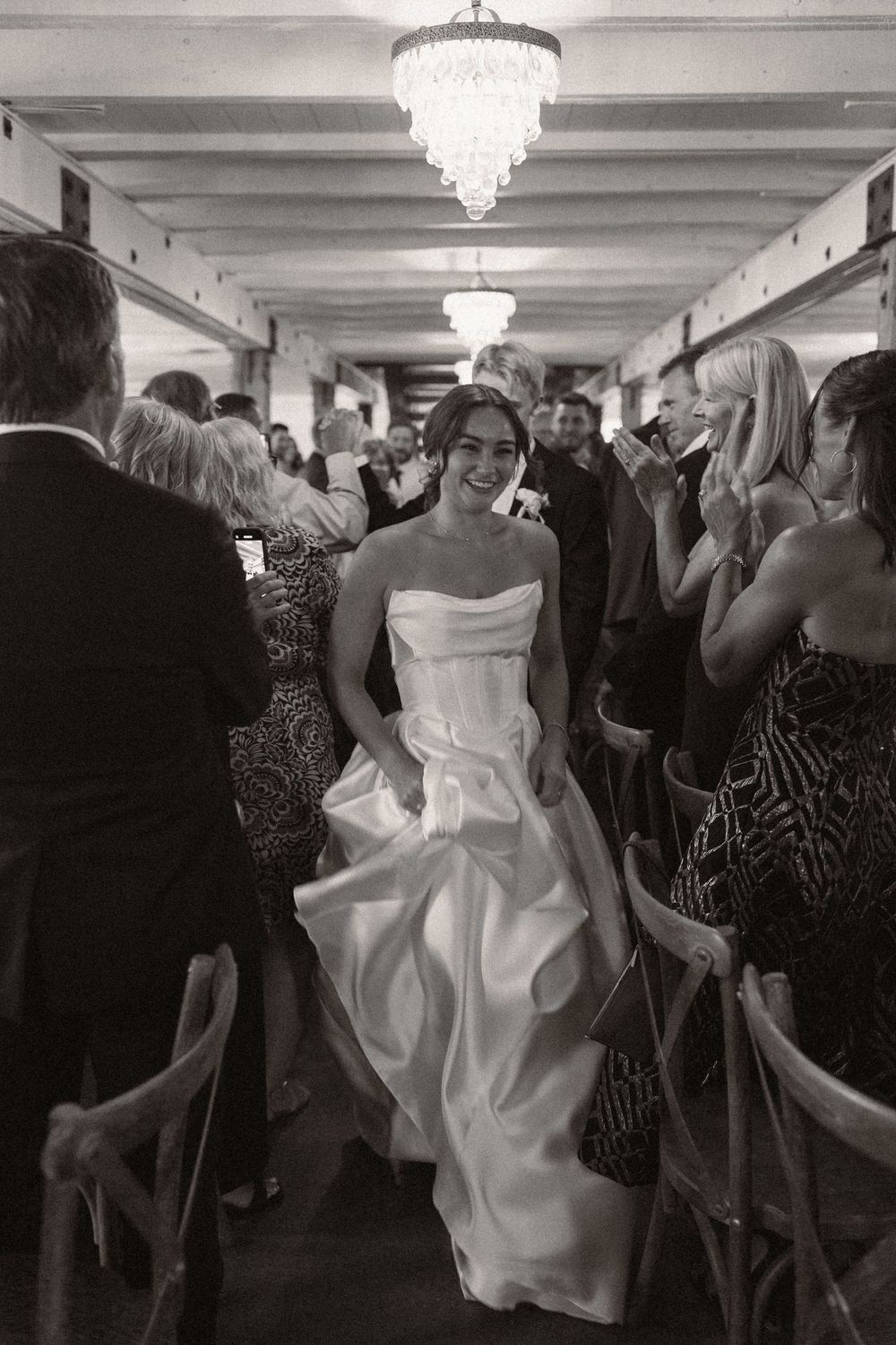 Wedding guests dance and celebrate on a reception dance floor beneath crystal chandeliers.