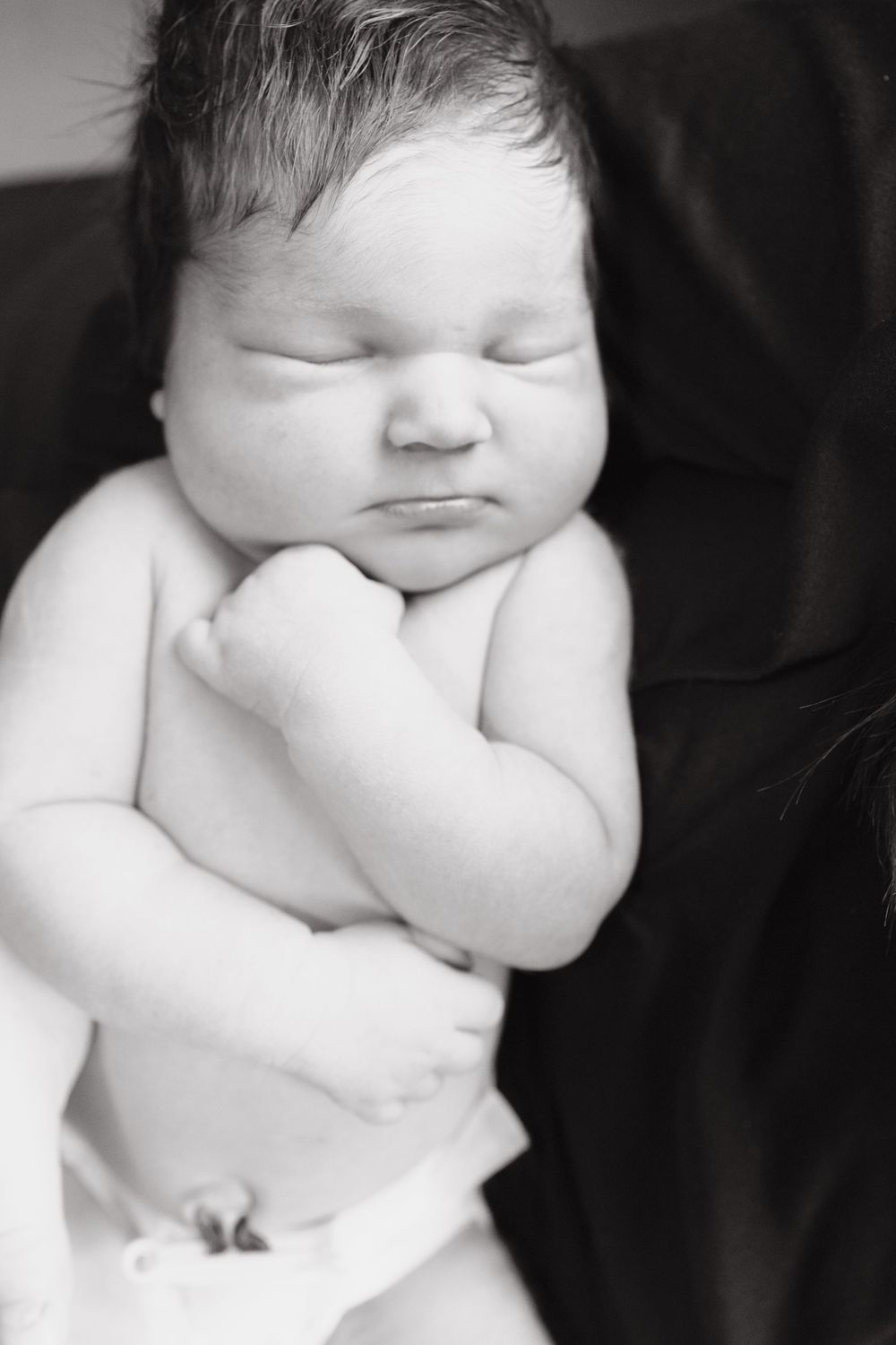 Black and white close-up portrait of a sleeping newborn baby's face.