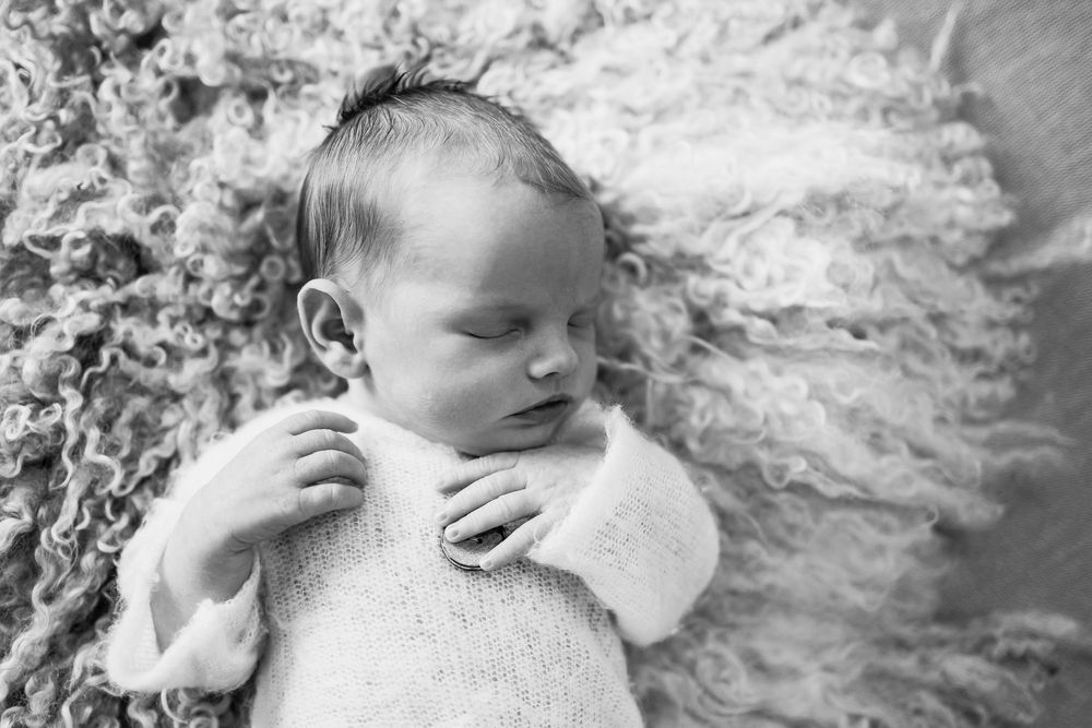 Artistic black and white portraits of sleeping newborn on textured background.