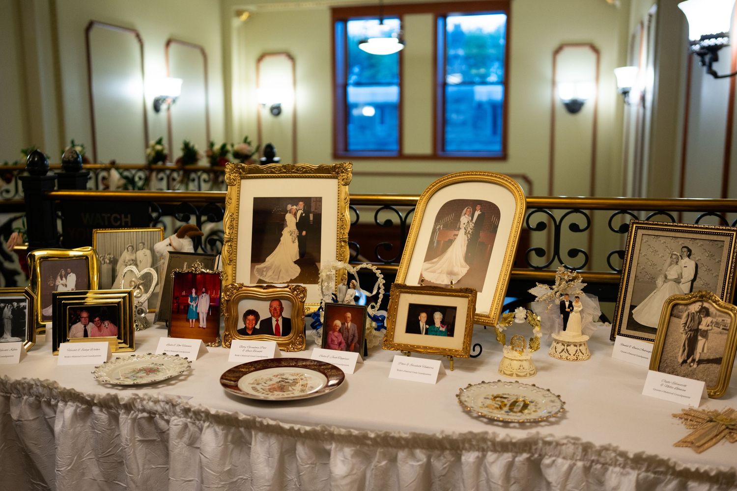 An elegant wedding reception table setup with framed photos and decorative elements illuminated by wall sconces.