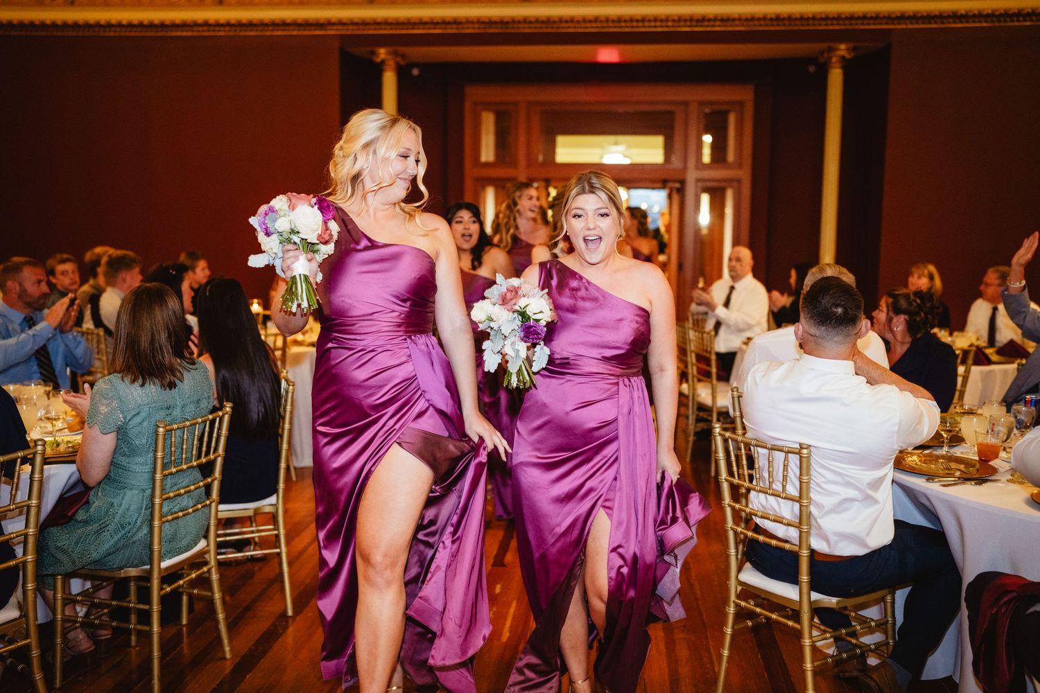 Guests dance and celebrate on a warmly lit ballroom floor during a wedding reception.