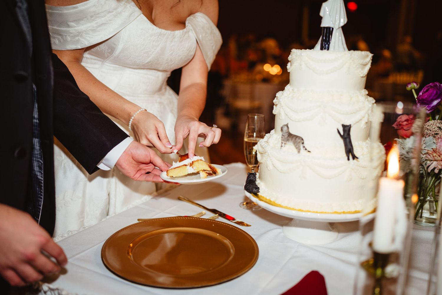 Close-up details of cutting and serving a traditional white wedding cake at a reception.
