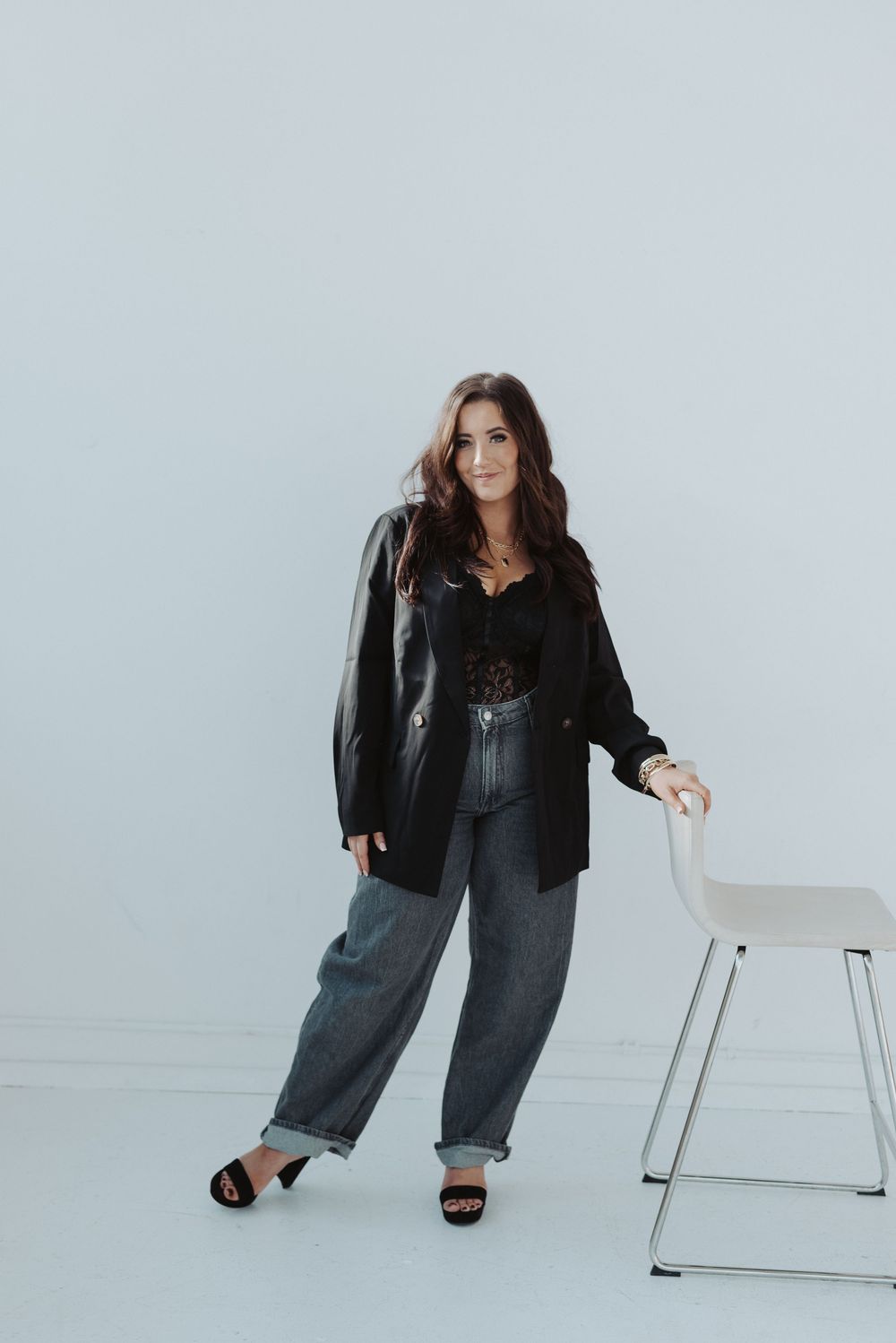 Casual fashion poses in black jacket and denim against minimalist white backdrop.