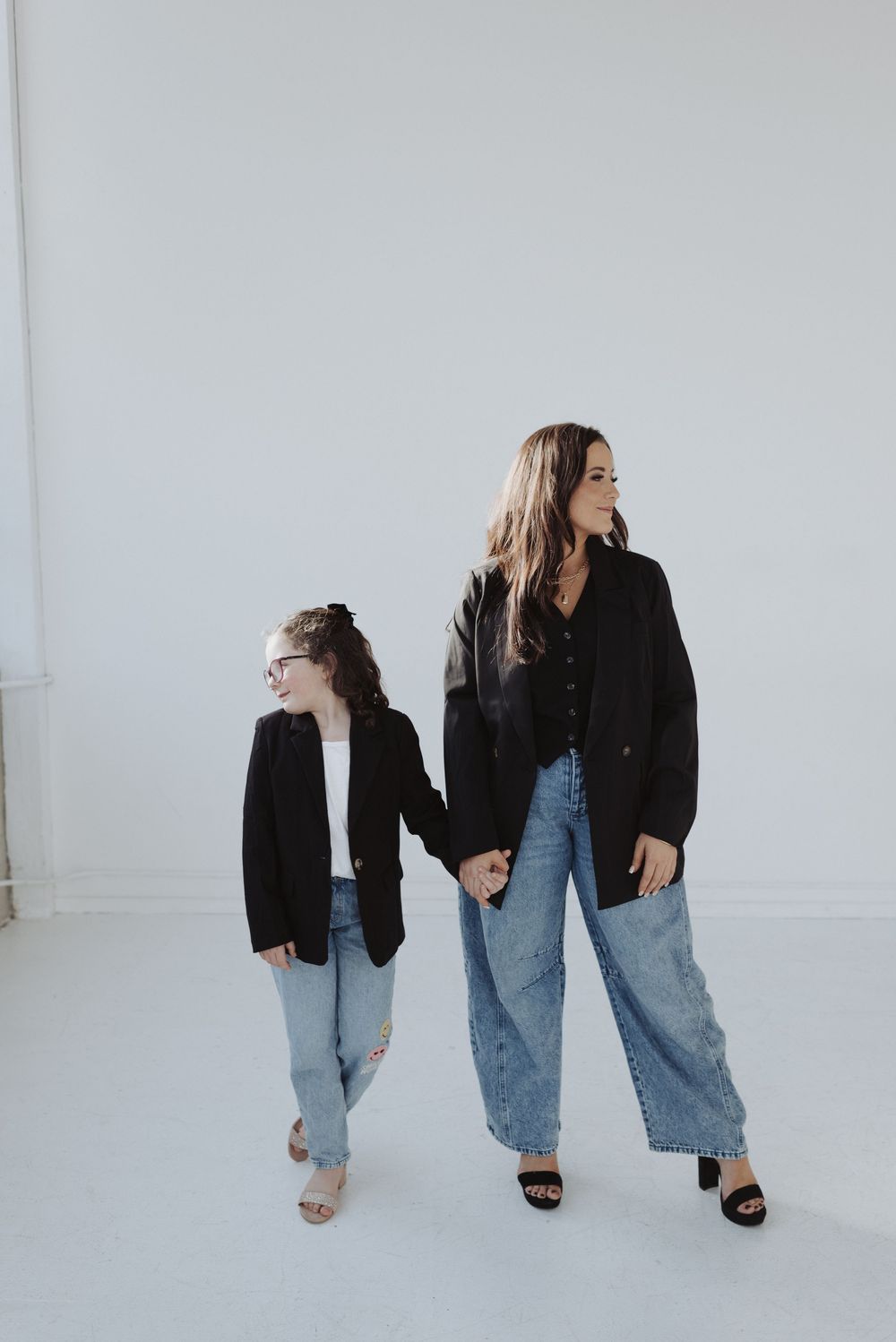 Fashion editorial style walking poses in denim and black against white backdrop.