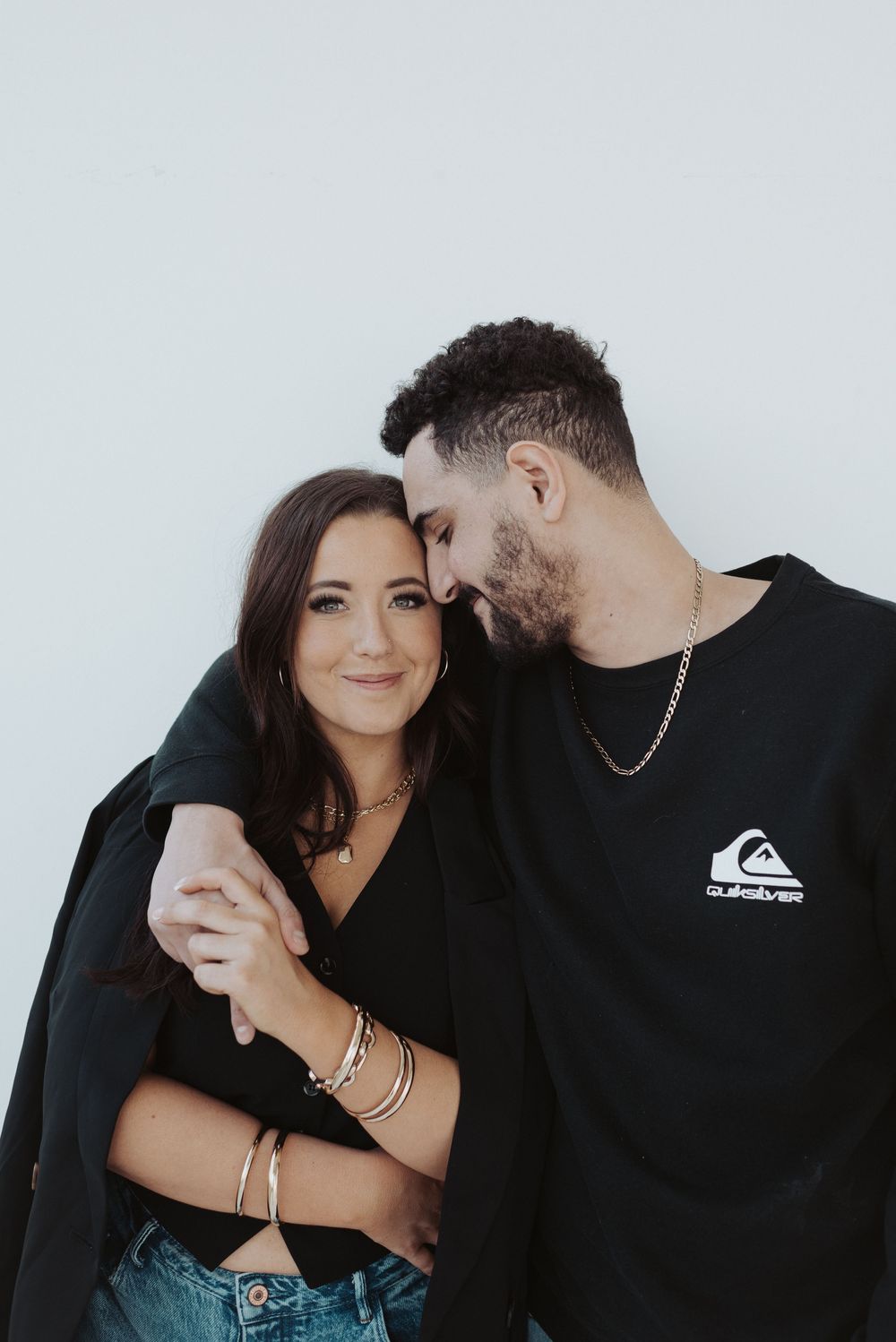 Romantic couple portrait session in black tops against minimalist white background.