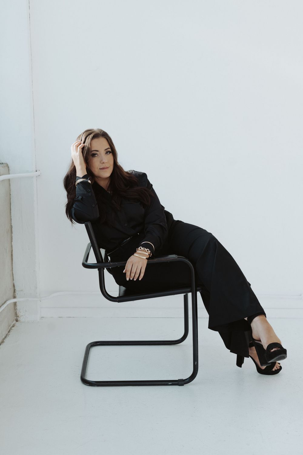 Artistic poses on a black chair showing relaxed movements in a minimalist setting.