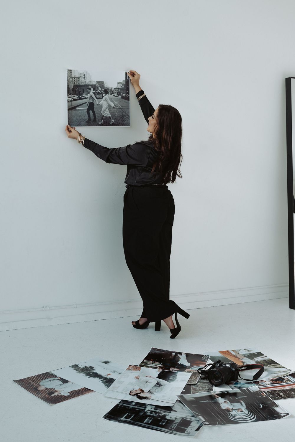 Creative sequence of arranging and hanging photographs on a white wall.