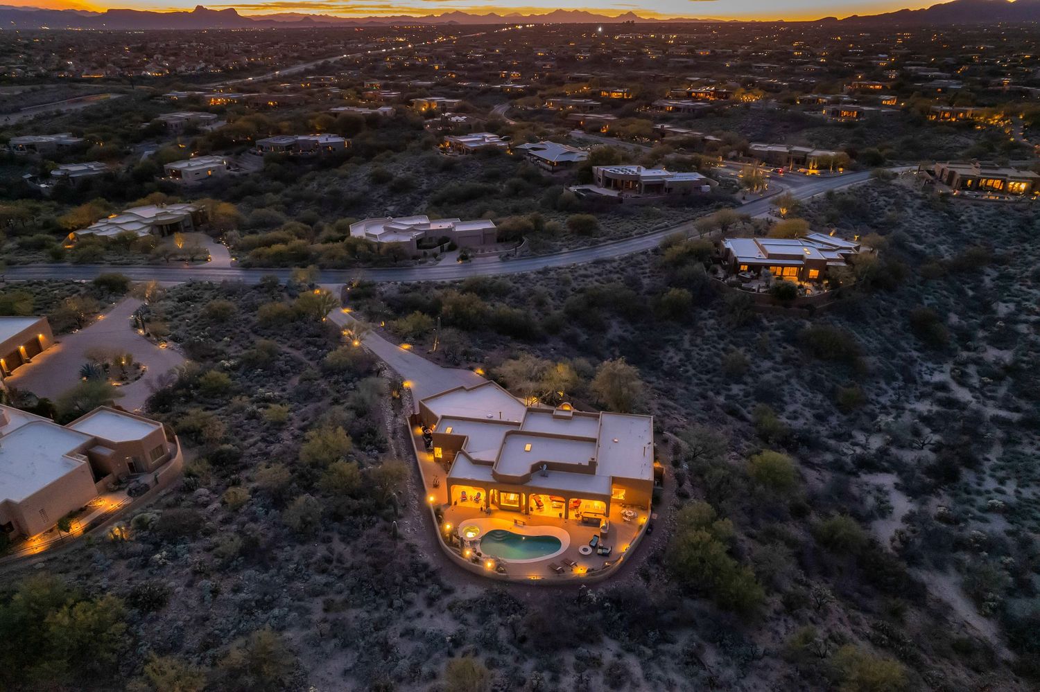 Aerial view of desert homes with glowing windows at sunset in Joshua Tree National Park.