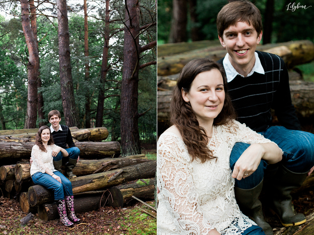 Casual engagement photos of a couple sitting on fallen logs in a pine forest.
