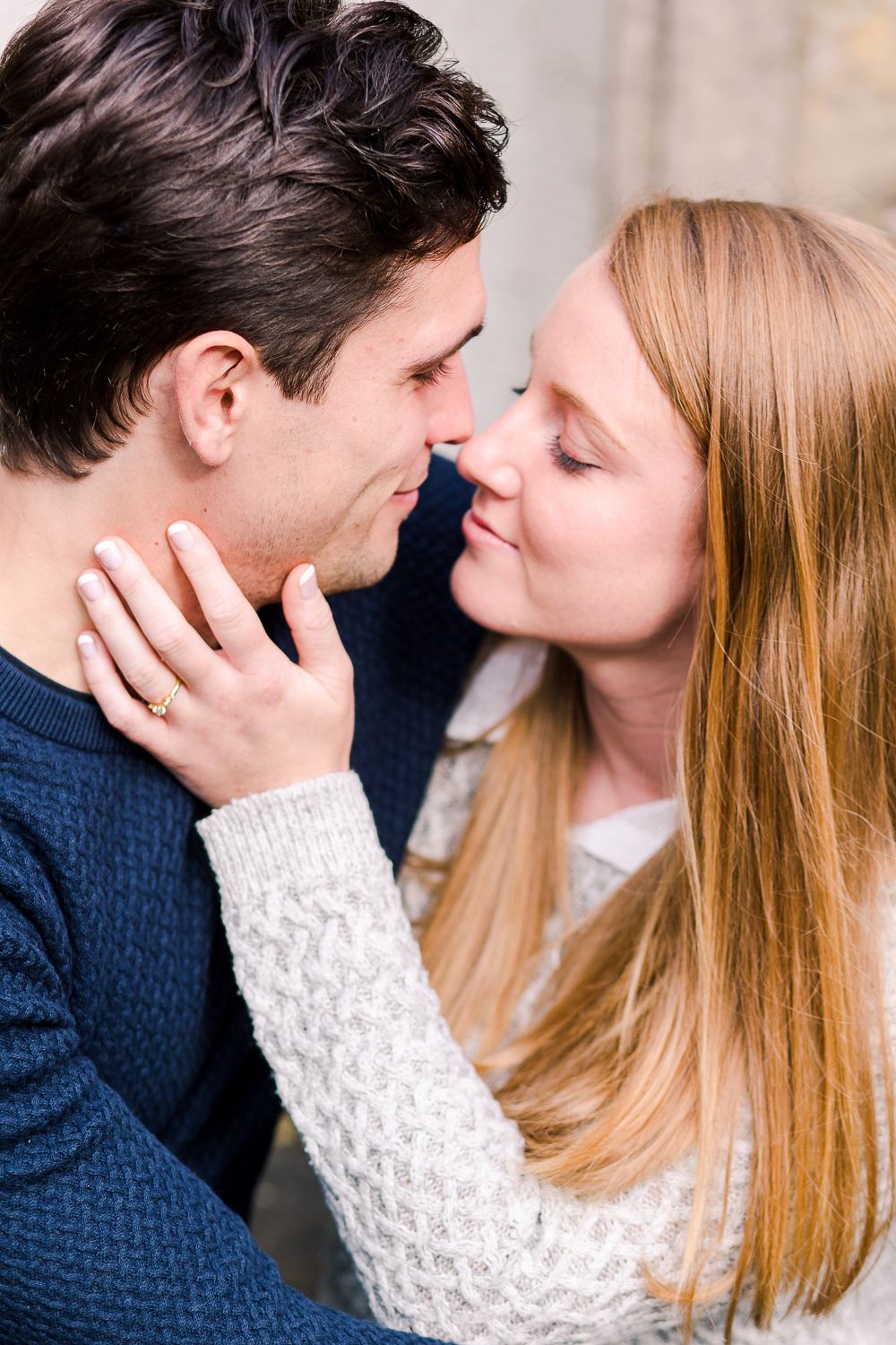 Romantic couple in navy and white sweaters share tender moments and kisses.