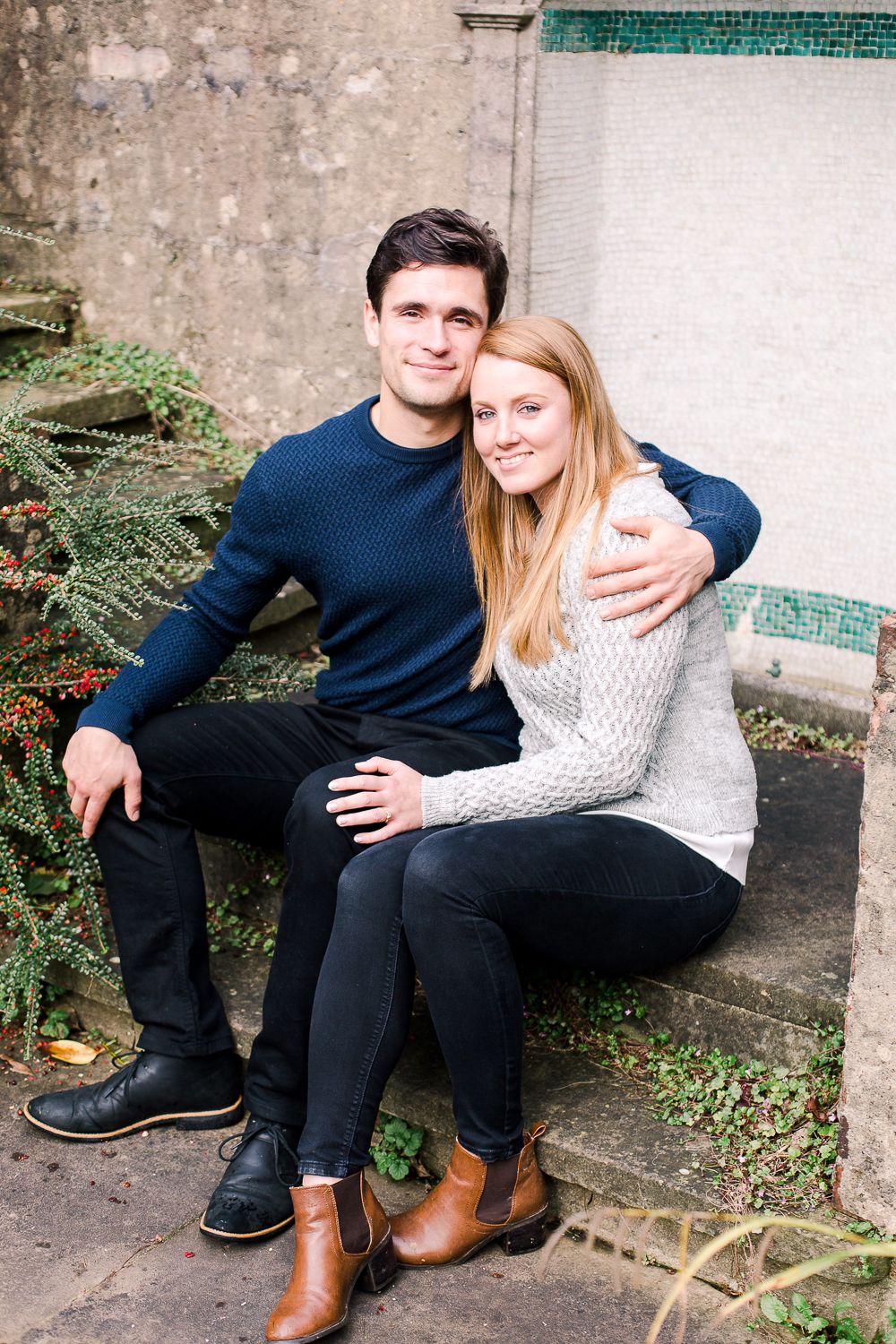 Couple sits together on concrete steps wearing coordinated navy and white outfits.