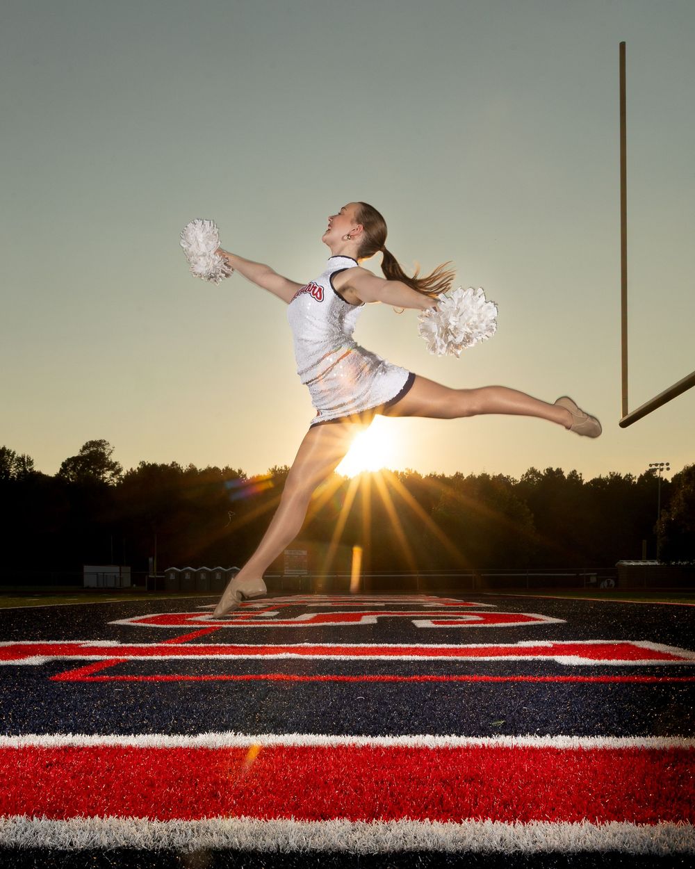 A dramatic series of cheerleading jumps captured at sunset on a football field with dramatic sunburst lighting effect.