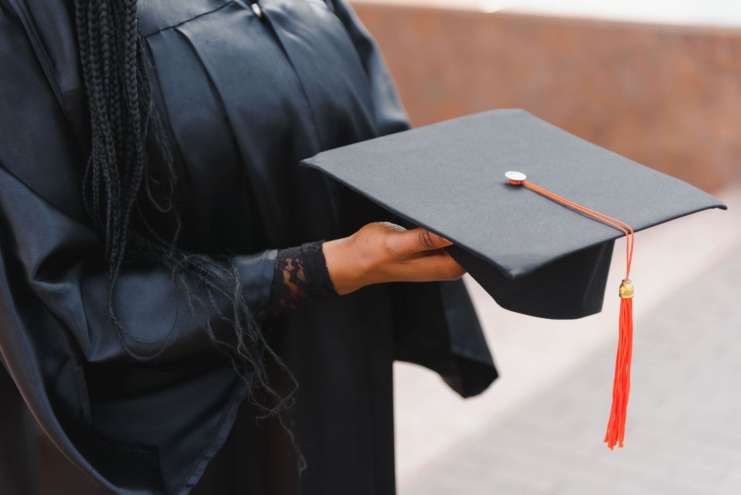Black graduation caps with red tassels are shown in different angles during a commencement ceremony.
