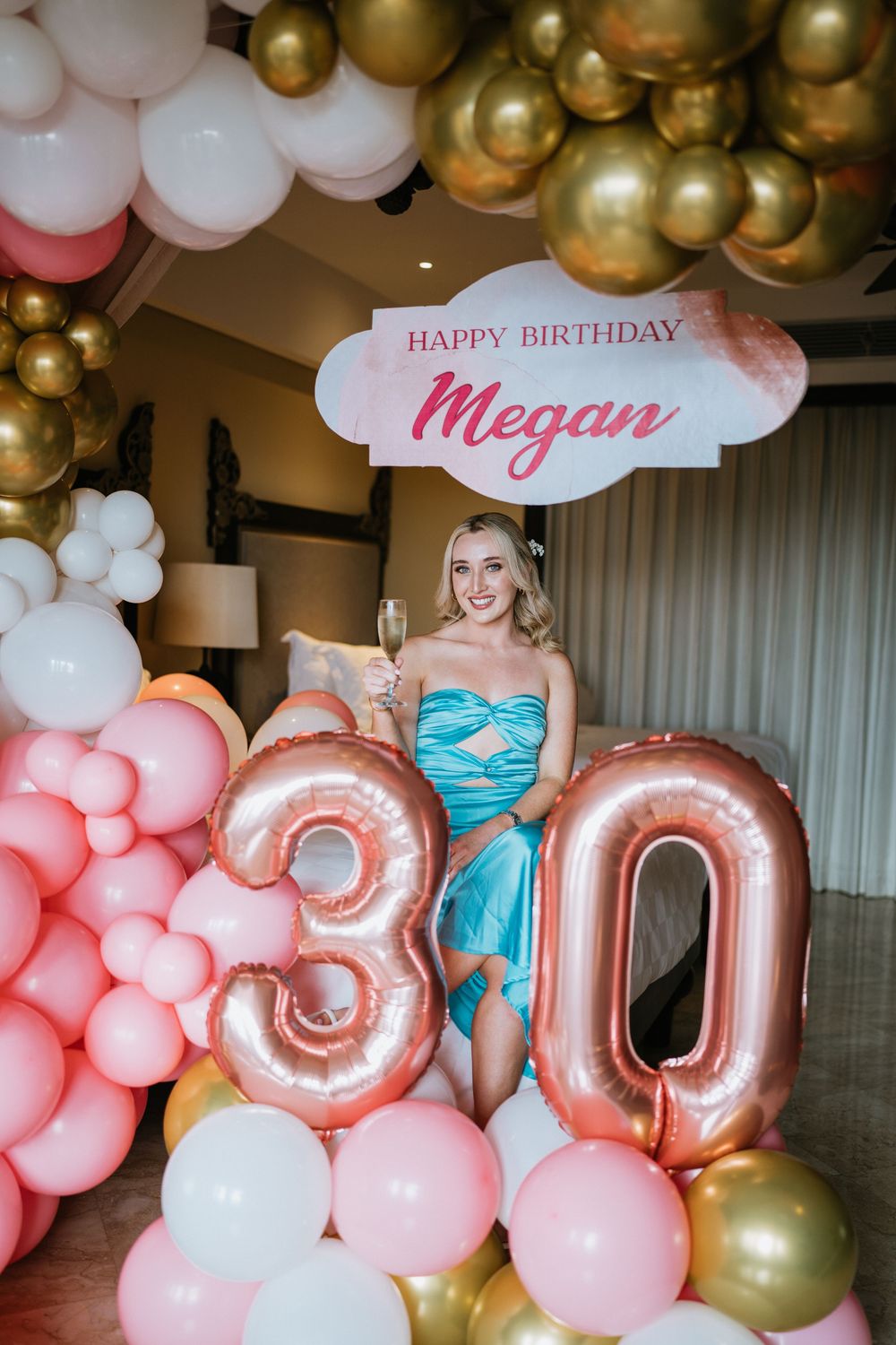 Festive birthday party decor with pink and gold balloon arch and custom name sign.