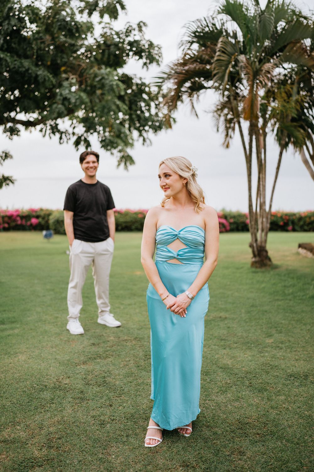 Scenic outdoor photoshoot on a grassy lawn with palm trees in the background.