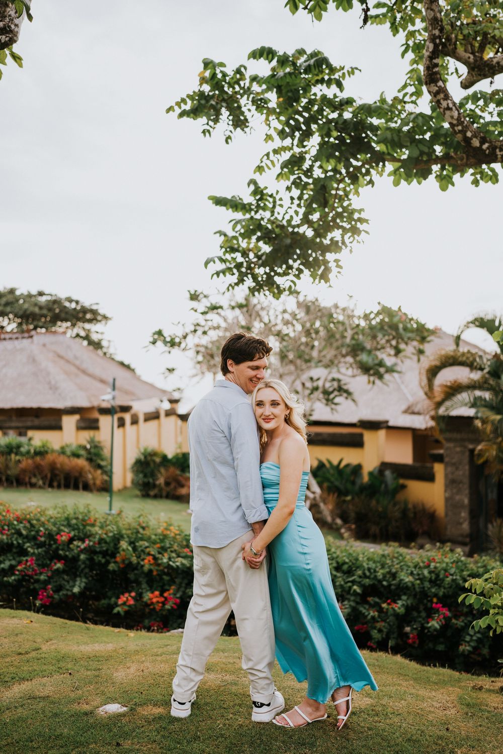 Couple sharing an intimate moment in a lush garden landscape.