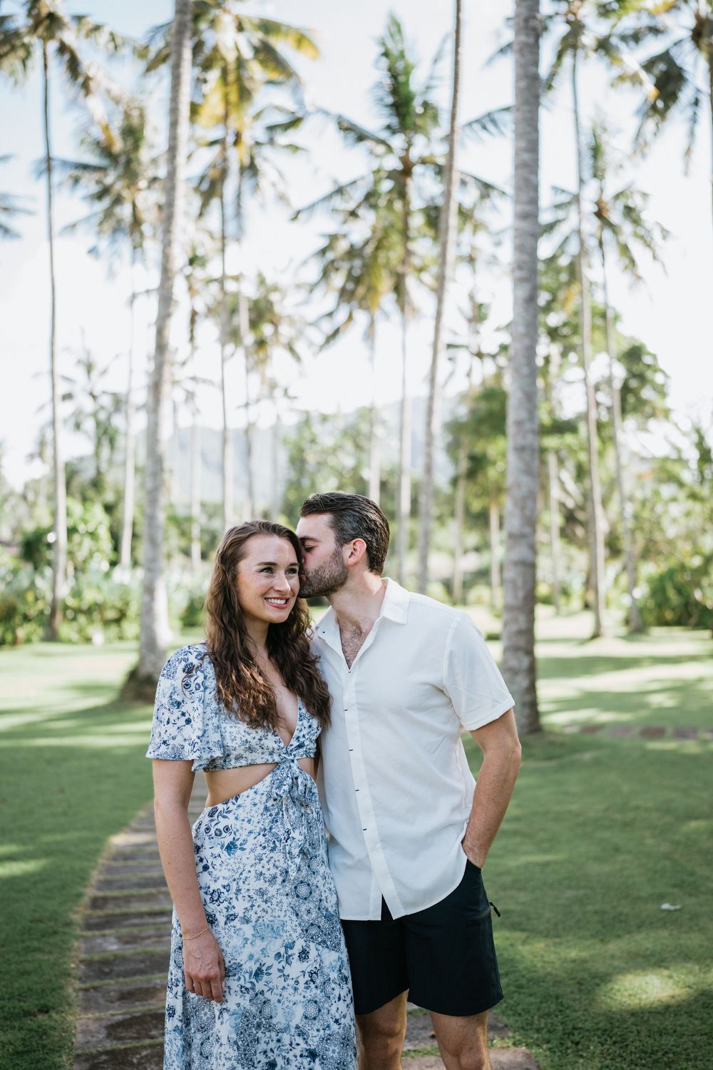 Couple strolling through a lush palm tree grove on a sunny day in Hawaii.