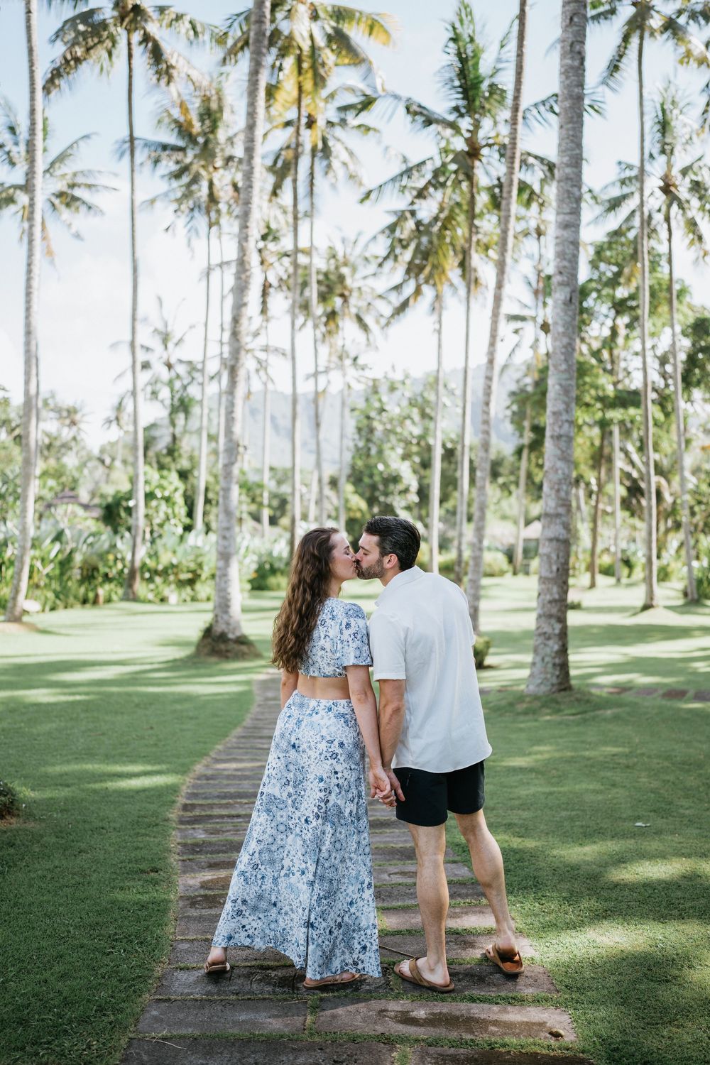 Romantic moment captured in a tropical palm grove with sunlight filtering through.