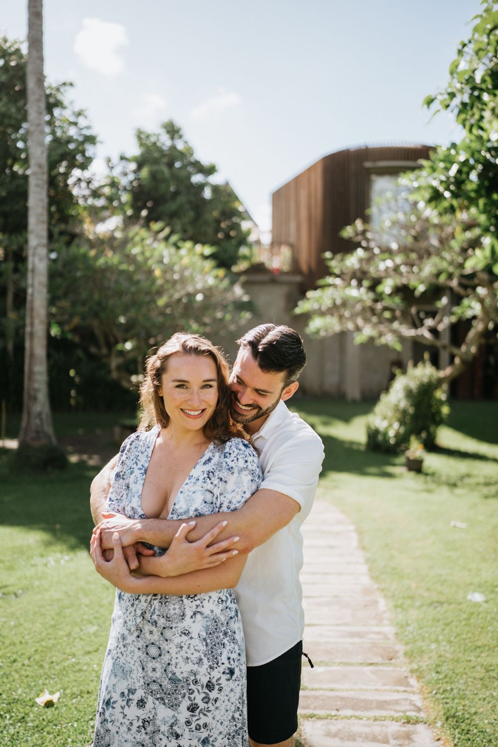 Tender embrace captured in a sunny tropical garden with palm trees.