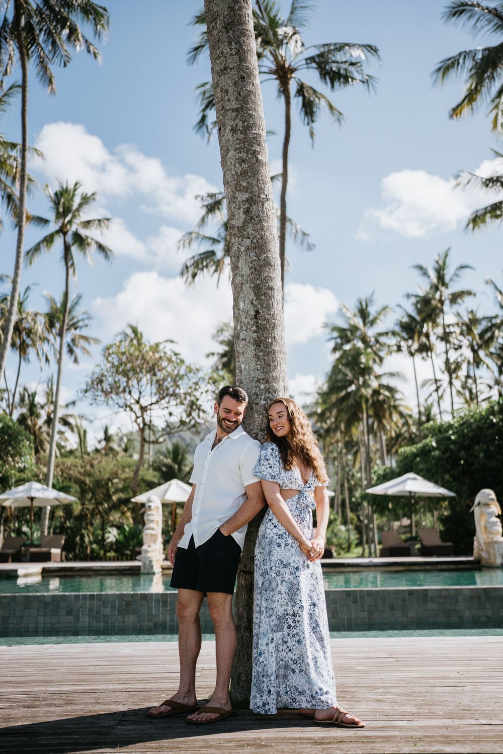 Couple enjoying tender moments on resort deck surrounded by tropical landscaping.