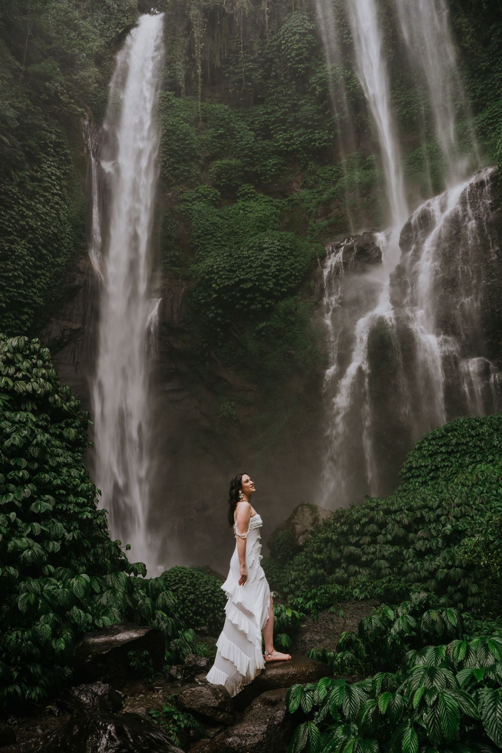 A scenic waterfall flows majestically through dense tropical vegetation creating a mystical atmosphere.