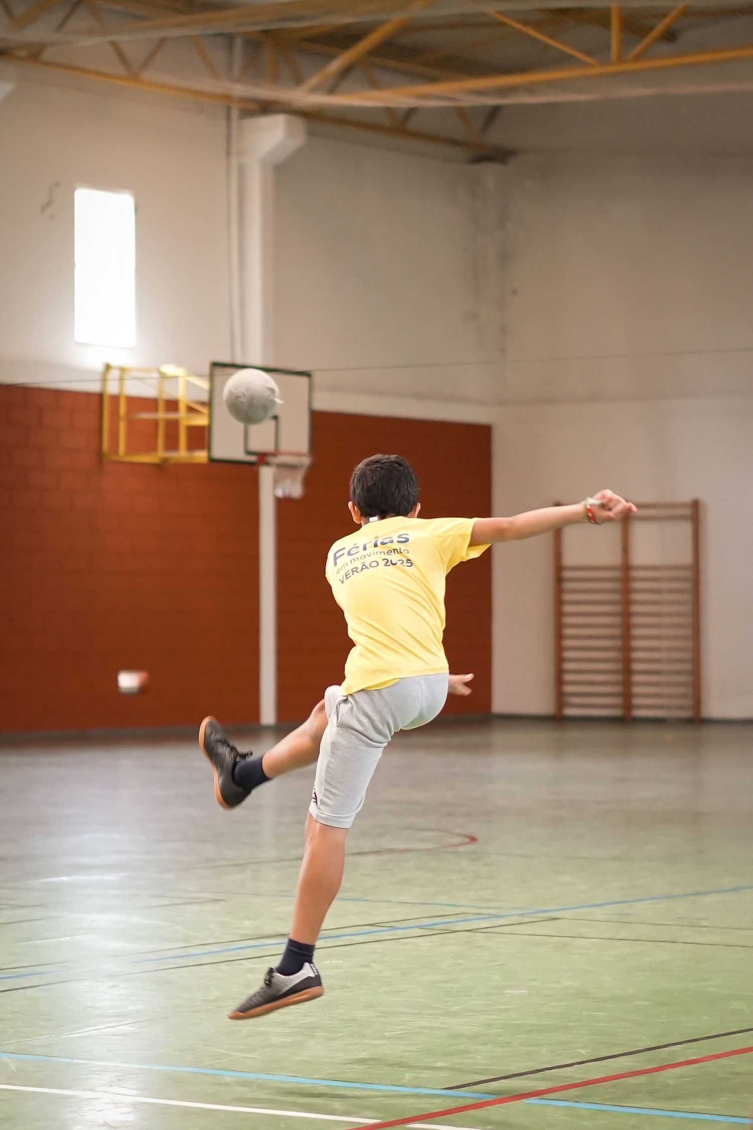Athletic figure in yellow shirt performing dynamic leaping movements across a gymnasium floor.