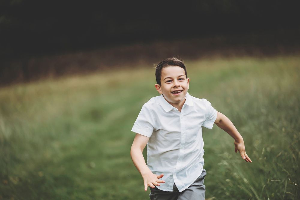 A series of joyful, candid action shots showing someone running playfully through a sunny grassy field.