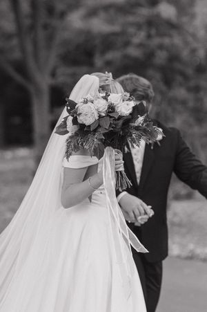 Wedding couple's embracing silhouettes in black and white with flowing bridal veil and floral headpiece detail.